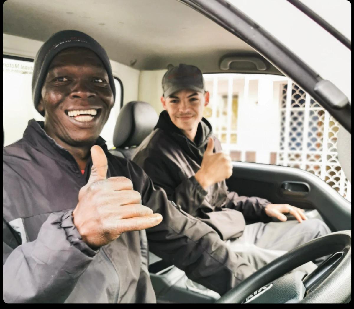 Two tradespeople smiling in a work vehicle